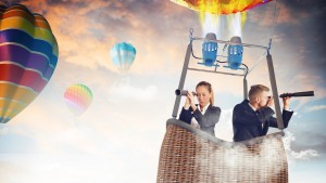 Businesspeople with binoculars in hot air balloon