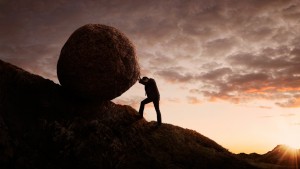 Businessman pushing large stone uphill