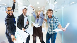Group of joyful business people throwing paper and having fun in office