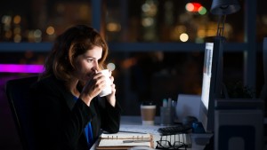 Businesswoman drinking coffee working overtime