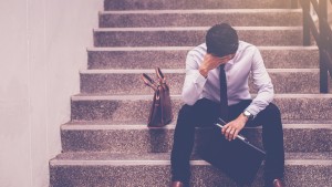 Stressed businessman sitting on stairway disappointed at job loss